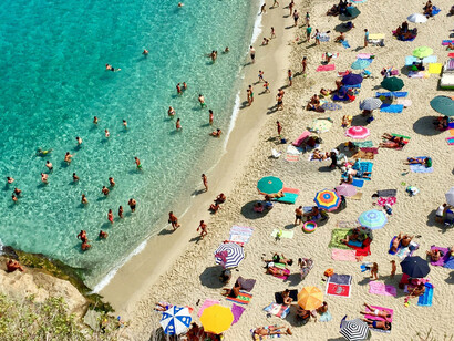 Sunbathers and swimmers at a popular beach in Tropea, Italy
