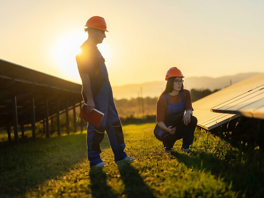 Technicians install solar panels on the roof of a residential building