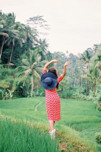 A woman walking through a tropical forest in Ubud, Bali, Indonesia, waving her hands in the ai