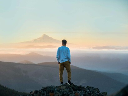 A man looking at the distance where the mountains stand firm and wondering what other obstacles must he overcome