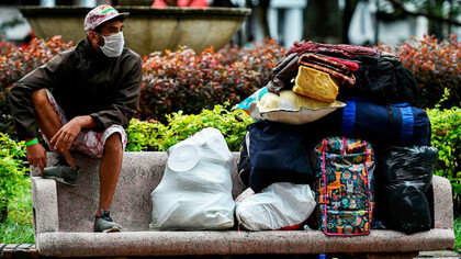 Migrante en un banco junto a sus escasa pertenencias en Santiago de Chile