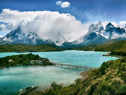 A serene mountain lake with a small island, set against the backdrop of snow-covered peaks in Torres del Paine National Park, Chile