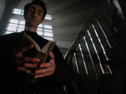 The holy book rests in the priest's hands, a vestige from ages long past