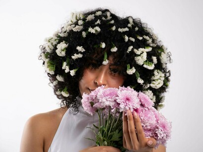 A woman holding a bouquet close to her face, reflecting the tenderness of self-acceptance
