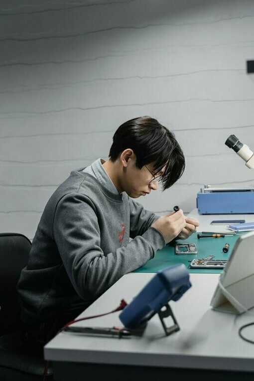A technician meticulously fixing an electronic device in a repair workshop, reflecting the shift from disposable technology towards sustainable reuse