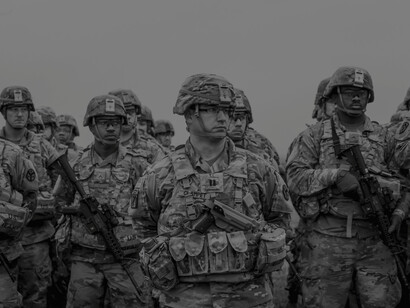 Men in military camouflage stand at attention 