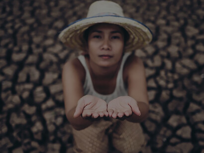 In the midst of parched surroundings during a period of global warming, the woman sat gazing at the sky, earnestly entreating for rain to quench the thirst of the arid landscape