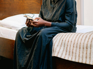 A man dressed in black stands holding a Bible, praying quietly