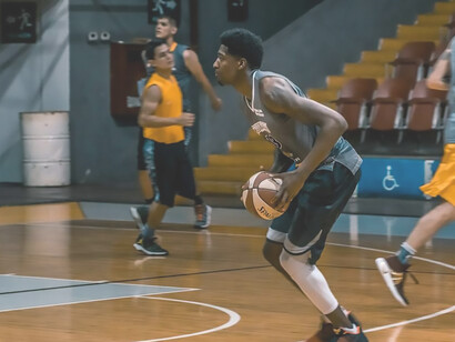 With a basketball in hand, a young man stands poised, embodying a sense of vigor and enthusiasm for the upcoming game