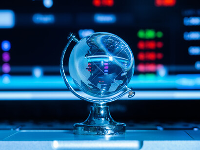 Mappamondo di vetro e grafici finanziari: "la guerra commerciale in atto è attiva ed è stata preannunciata"