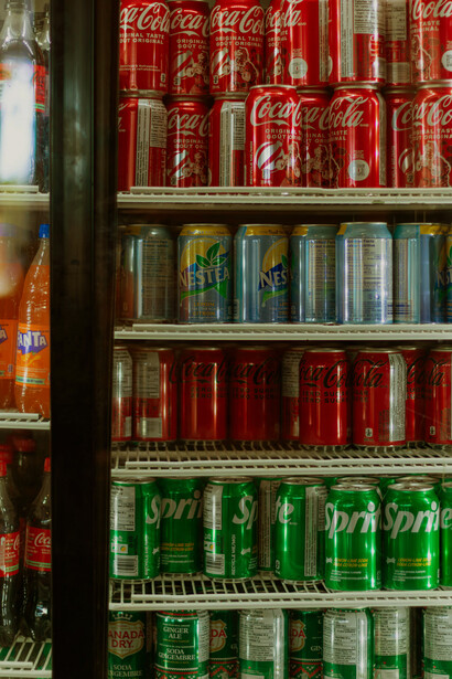 Colorful soda cans lined up in a fridge, highlighting the abundance of sugary beverages in modern diets