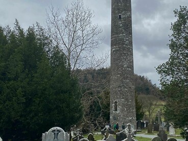 La famosa Torre Redonda de piedra domina el paisaje del antiguo cementerio monástico. Glendalough, Irlanda