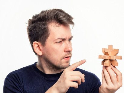 As the man struggles with the wooden puzzle, it highlights how cognitive biases and emotional decision-making can affect choices