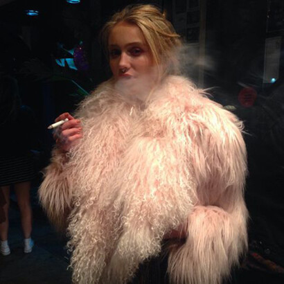 A woman smoking a cigarette in a pink furry jacket