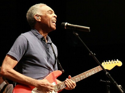 Gilberto Gil canta e toca guitarra durante apresentação no Festival de Cornouaille, em Quimper, na França, em 2010. Entre o sorriso e a música, o palco registra um dos muitos momentos em que o artista se tornou presença constante na memória afetiva de diferentes gerações