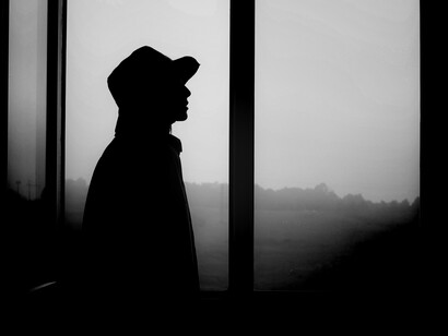 Silhouette of an individual standing in front of a window