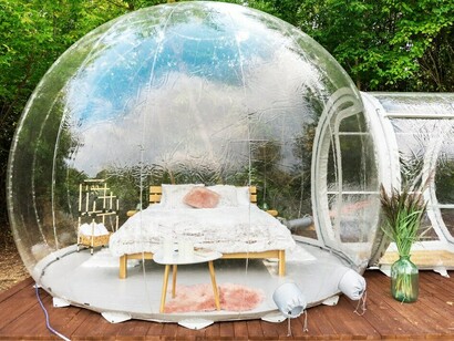 Relaxing in a transparent bubble tent at a glamping retreat, with geodesic domes enhancing the eco-friendly hotel experience