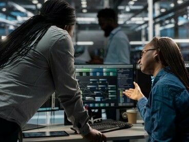 Analysts monitor global data across multiple displays in a decision-making room, forming a strategic environment where professionals work in real time