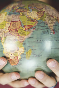 A person gently cradles a small globe in both hands, symbolizing a deep connection to the world and a commitment to global awareness and cultural understanding