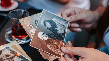 Mãos percorrem fotografias em caixa de recordações
