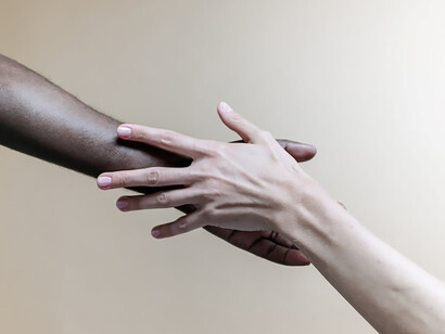 Two people holding hands, reaching out to each other in a poignant display of connection and solidarity