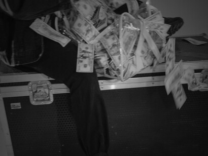 Person sitting on a chest while holding cash