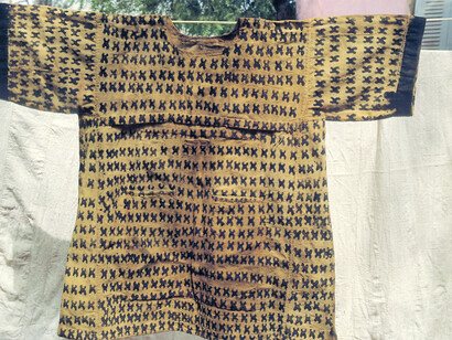 Ill. 64. The “Blacksmith’s tongs” (Baronw), or “Escape” (Tala) or Wope, meaning unknown. The name Wope is used around Sienro (not on maps), a village northeast of Segu. A seventy year-old hunter originally from the Dioila region told Mr. Mara that this design represented a blacksmith’s tongs. He explained that “with tongs you can handle both cold and hot objects. When you hunt in the bush there are cold days when you win out over the animals and then there are hot days when the animals win out over you”. The design can also mean that you have encountered a great danger in the bush and you have escaped it; ka tala means “to escape something.” The design can also be interpreted as a reference to the crossroads (dankun) where hunters make their sacrifi ces. The elderly woman who called the design Wope added that this was when it was painted on hunters’ shirts. On women’s wrappers the same pattern was called San kaba or “Cloudy sky” and it signified that forty days had passed since a woman’s husband had died.  
Photocredit Sarah C. Brett–Smith
