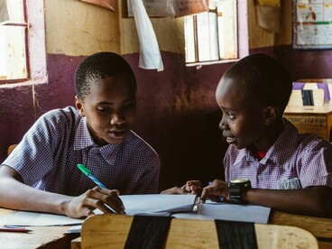 Des élèves apprenant ensemble à leur pupitre, symbolisant le rôle des écoles dans la formation de la prochaine génération de citoyens