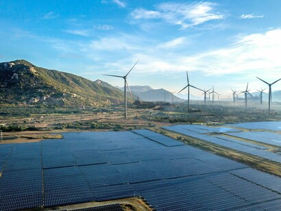 Rows of wind turbines rising beside expansive solar panels, symbolising the shift toward sustainable infrastructure as a pillar of strategic autonomy