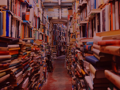 Un chemin entre des livres empilés met en avant l'atmosphère accueillante et riche en savoir des librairies et événements littéraires à Marseille