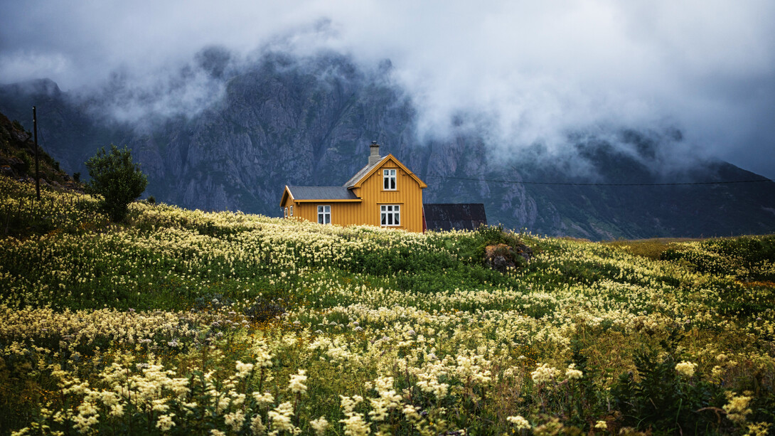 Solitaria casa en medio de una pradera frente a un paisaje montañoso