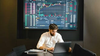 Trader analisando gráfico da bolsa de valores no laptop