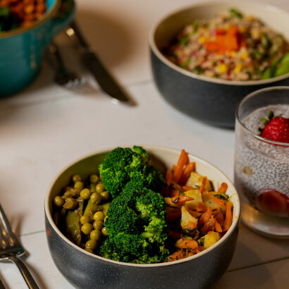A colorful mix of sliced fruits, quinoa, and garden-fresh vegetables beautifully arranged in a black ceramic bowl, representing balanced and low-calorie nutrition