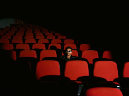 A man sitting inside a cinema while wearing sunglasses