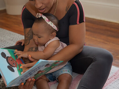 On the floor, a person shares heartwarming moments of play with a delightful baby