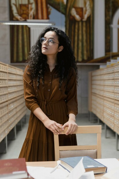 A reader standing in a library, symbolizing the intimate relationship between audiences and the stories they choose to explore