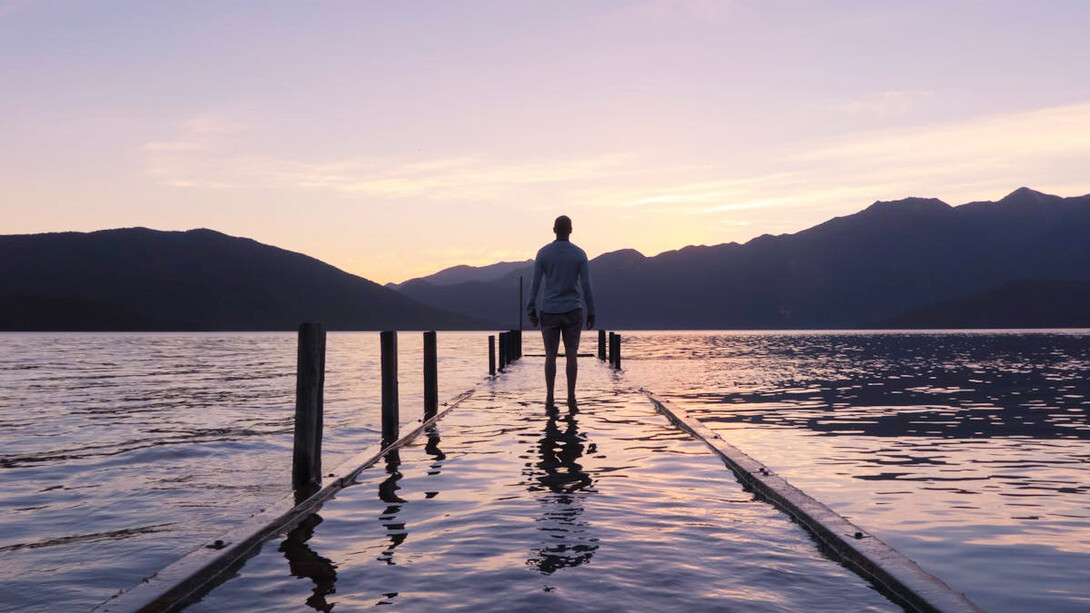 The tranquil scene of a person staring out over a body of water encapsulates the diverse philosophies on suffering, from Buddhism’s call for embracing both pleasure and pain, to Stoicism’s focus on control, and Islam’s emphasis on faith amid life's struggles