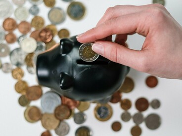 A hand dropping a coin into a piggy bank, symbolising modern approaches to alternative investing