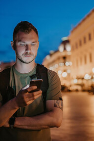 A tourist man walking while checking his social media during his trip