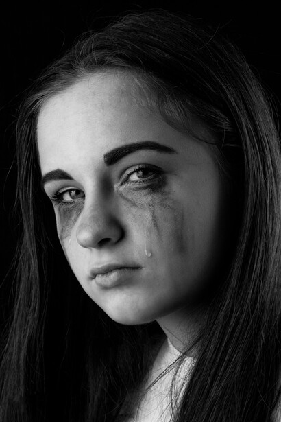 Monochrome image showing a girl in tears, her expression marked by sorrow and despair