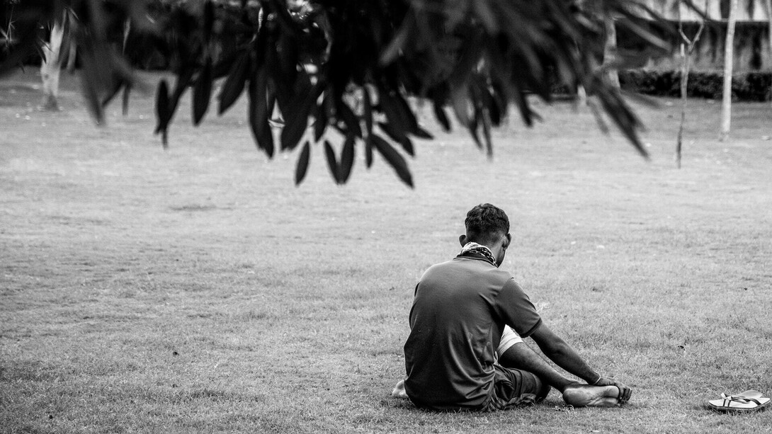 Homem sentado ao chão, desolado. A tristeza que pode ser causada por distorções da sociedade