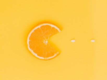 On a vibrant yellow and orange backdrop, a refreshing slice of citrus, accompanied by a half-filled arrangement of vitamins and pills, encapsulates the essence of health and creativity