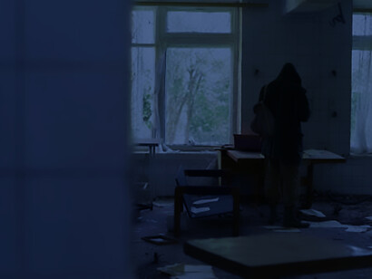 Amidst the desolation of a war zone, an individual is captured in an abandoned building, emblematic of the resilience and struggle for survival amidst adversity