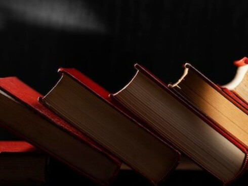 An aesthetic arrangement of antique books rests on the wooden table, showcasing their timeless elegance and character