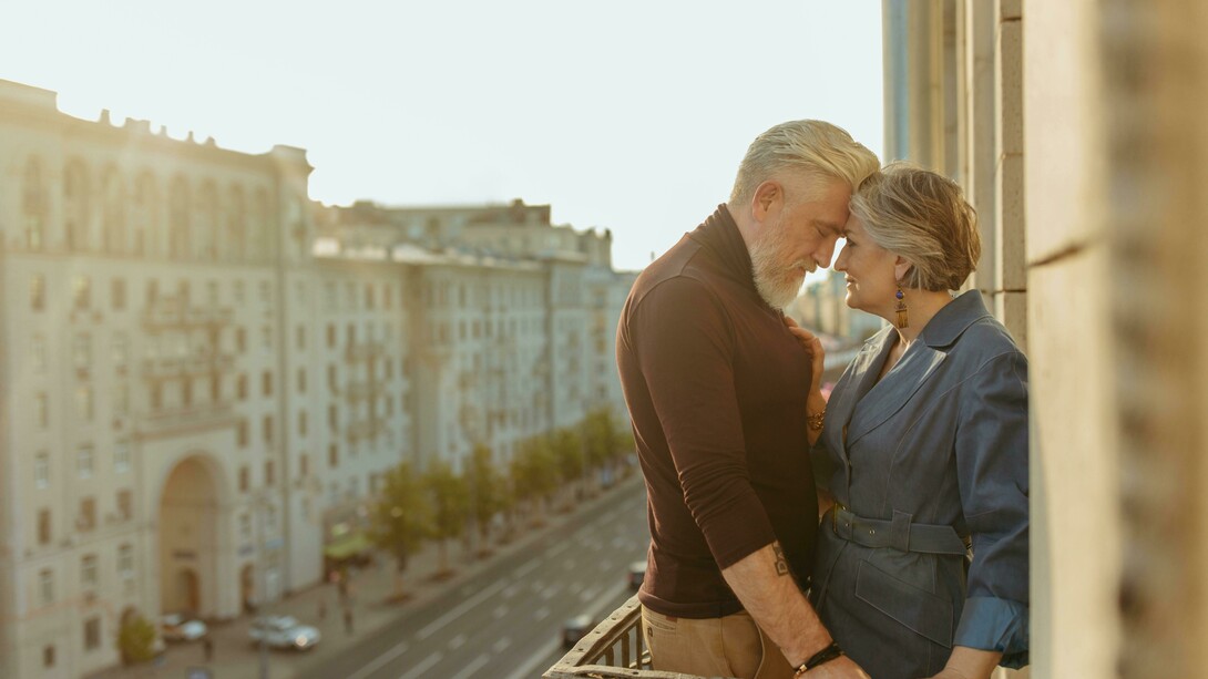 An elderly couple on a balcony, captured in a quiet moment as they share a kiss