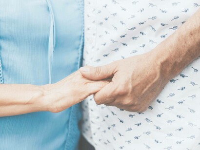 A patient holding the hands of their loved one after beating their co-infections