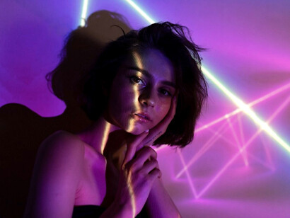 Vibrant neon-lit portrait of a teenage girl, evoking the atmosphere of avant-garde performance art