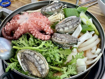 A seafood stew, brimming with shellfish and vegetables, mirrors the immersive Jeju Island experience of discovering bold local flavors in every bubbling pot