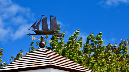 Veleta con forma de barco encima del techo de una cabaña