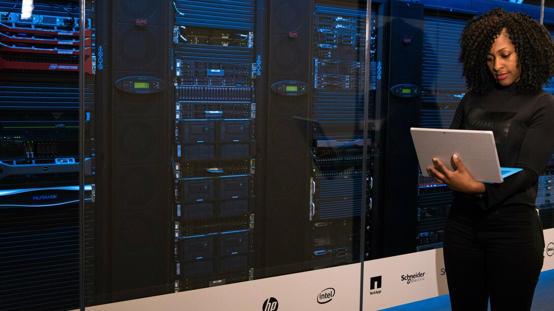 A woman standing up holding a laptop